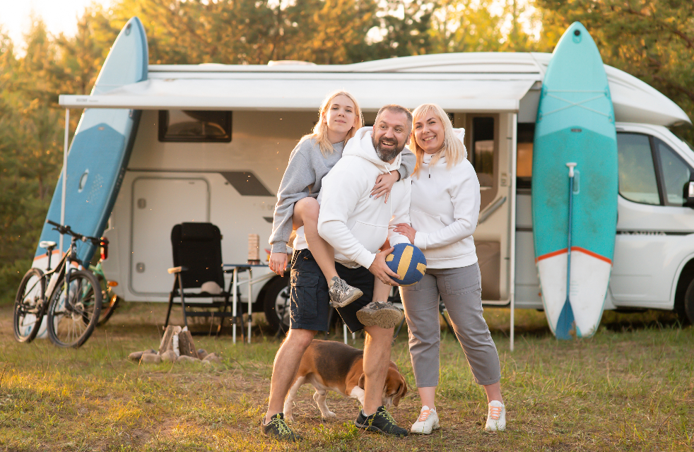 Des parents heureux avec leur enfant jouant au ballon près de leur mobil-home à seignosse