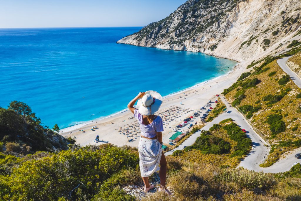 Femme heureuse debout au sommet d'un rocher avec chapeau profitant de la plage de Myrtos. île de Céphalonie, Grèce